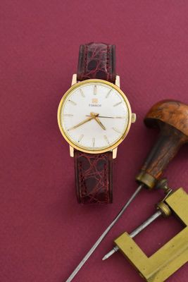 une montre posée sur une table à côté d'une paire d'outils