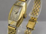 une photo d'une montre-bracelet en or posée sur un socle transparent
