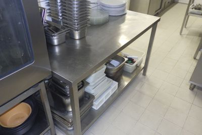 une cuisine avec une table en inox sur laquelle sont posées des assiettes et des casseroles