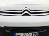 the front end of a white car with a number plate on it