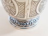 a silver vase with a design on it on a white surface