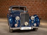 a blue car that is parked in front of a brick wall