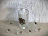 quatre verres à shot et une carafe posés sur une table