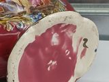 a red vase with a floral design on it sitting on a table