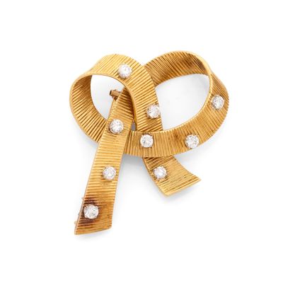 un gros plan d'une broche en forme de nœud en or sertie de diamants, sur fond blanc