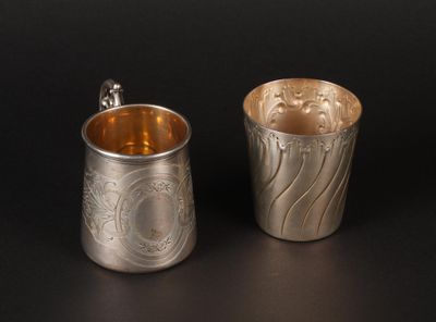 two silver cups with designs on them sitting next to each other