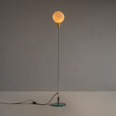 un lampadaire avec un pied en verre et une ampoule au sommet