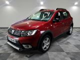 La Dacia rouge est garée sur un sol en carrelage à damier.
