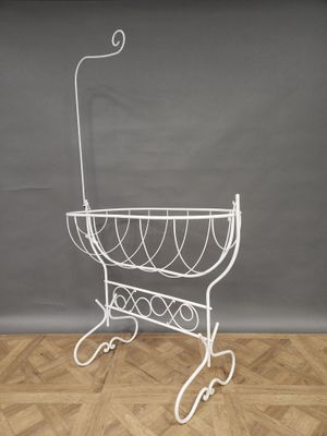 white wire basket on stand on wooden floor against grey wall