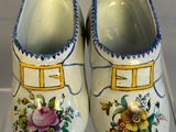 pair of clogs with flowers painted on them on display in a glass case