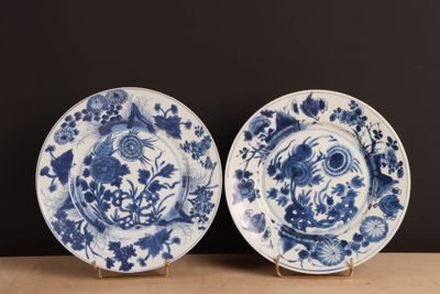 two blue and white plates with flowers on them on a table