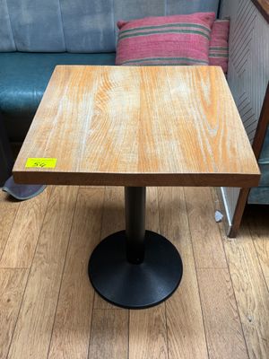 une table en bois avec un piètement en métal noir posée sur un parquet