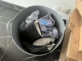 a bucket full of clothes sitting on the floor next to a pile of boxes