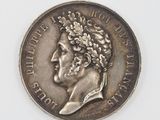 une vieille pièce d'argent sur laquelle figure le portrait d'un homme coiffé d'une couronne de fleurs
