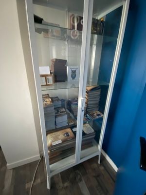 a glass display case filled with books in the corner of a room