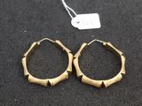 two pairs of gold hoop earrings on a black surface