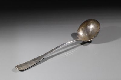une cuillère en argent posée sur une surface blanche, avec une ombre qui se projette dessus