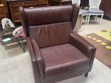 a brown leather chair in a living room with a rug on the floor