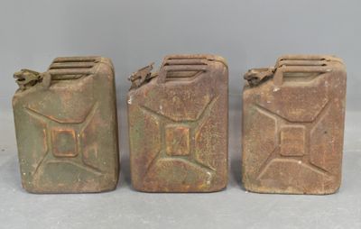 three old jerry canisters are lined up on a table