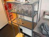 a metal shelf with wine glasses on it in a kitchen