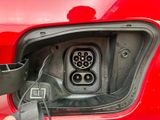 an electric car plugged in to a red car with a black cord