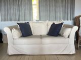 a white couch sitting in a living room next to a window