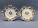 deux assiettes ornées de motifs dorés et blancs sur un fond gris