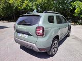 a green car parked in a parking lot with trees in the background
