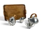 trois théières en argent et un plateau posés sur une surface blanche