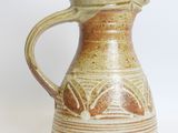 a brown and white pitcher sitting on a white surface