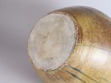 a close up of a brown and green vase on a white surface