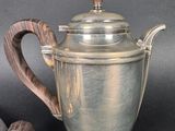 a silver tea pot with a wooden handle on a table