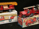 trois camions de pompiers miniatures posés les uns à côté des autres sur un fond noir
