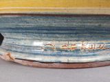 un vase bleu, jaune et marron, sur lequel figure une inscription