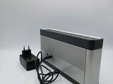 a silver and black speaker sitting on a white surface