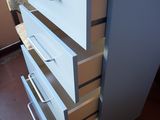 a tall white dresser with four drawers on it