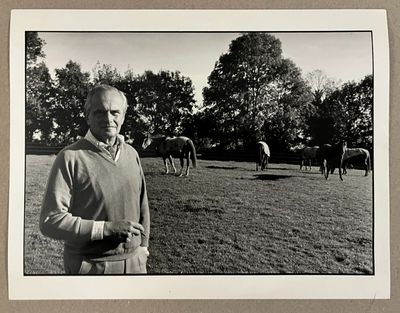 photographie en noir et blanc d'un homme debout devant un troupeau de chevaux