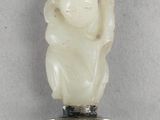 une image représentant une statuette en jade blanc posée sur un socle en argent