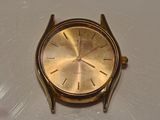a gold colored watch sitting on a white surface