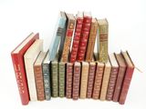 several old books are stacked on top of each other on a white surface