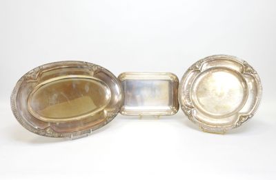 trois plateaux argentés posés sur une surface blanche, avec un miroir au milieu