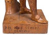 a wooden statue of a man with his foot on a stool