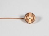 a close up of a gold pin with a pearl on it