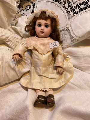 a doll that is sitting on a bed with a lace doily