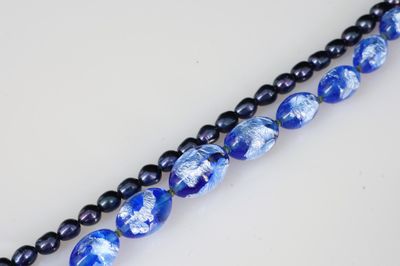 deux rangées de perles de verre bleues et noires sur un fond blanc