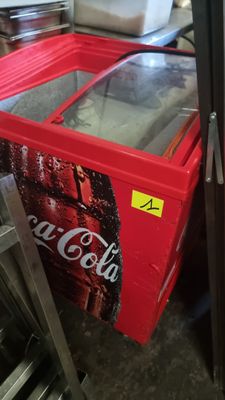 a red cooler sitting next to a refrigerator in a room