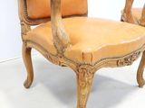 leather upholstered chair with carved wood frame and arms