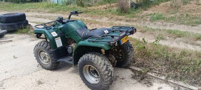 une photo d'un quad vert garé sur le bord de la route