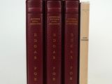 trois livres rouges empilés les uns sur les autres à côté d'une boîte en carton