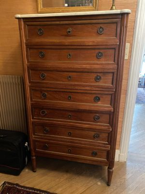 une commode avec un miroir et une valise posée par terre